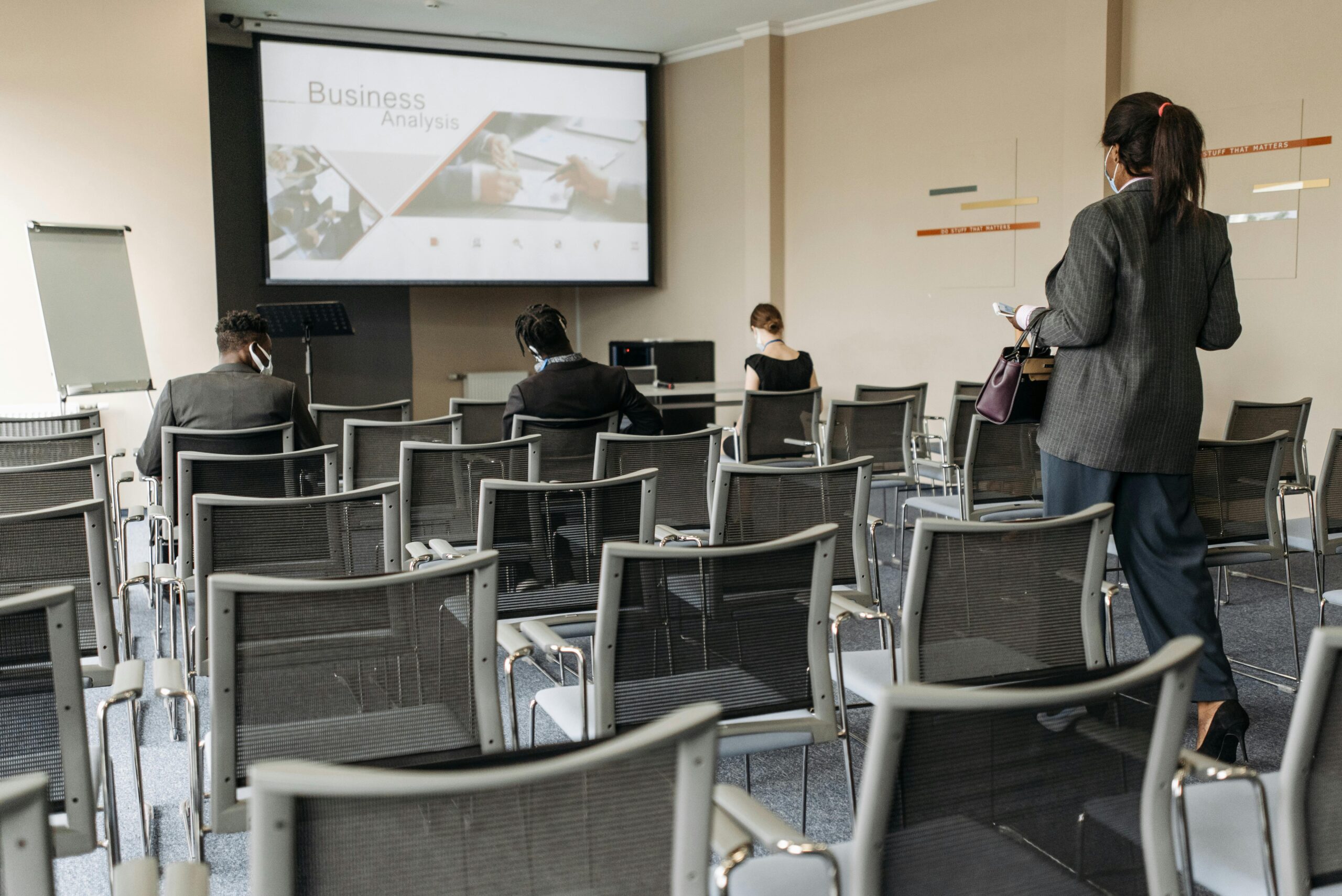Conference room setup for a business seminar, with attendees wearing masks.